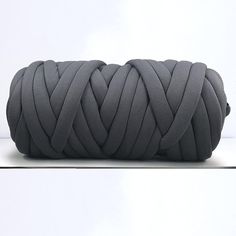 a roll of gray colored rope on top of a white surface with one knoted up in the middle