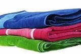 towels folded on top of each other in different colors and patterns, all stacked together