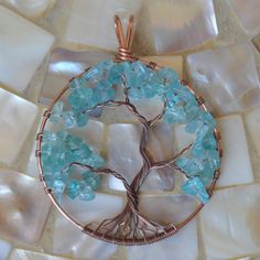 a tree of life pendant is shown on a mosaic tile background with white and blue stones