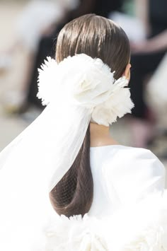 the back of a woman's head wearing a white veil and flower in her hair