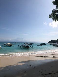 several boats are docked on the beach in clear blue water