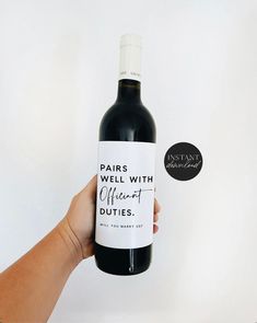 a hand holding a bottle of wine that says pairs well with different duties