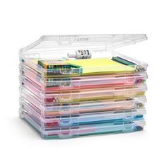 a stack of plastic storage containers filled with lots of different colored papers