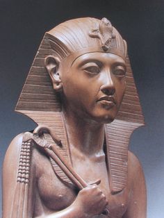 a statue of an egyptian woman with her hands in her pockets and wearing a necklace