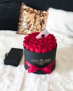 a black box filled with red roses next to a pillow