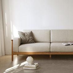 a white couch sitting on top of a hard wood floor next to a book shelf