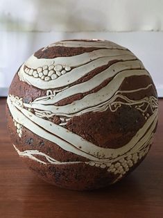 a brown and white painted rock sitting on top of a wooden table next to a wall