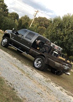 a large truck parked on the side of a road next to some trees and grass