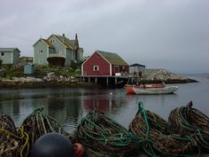 there are many fishing nets in the water near some houses and boats on the shore