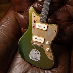 a green guitar sitting on top of a brown leather chair