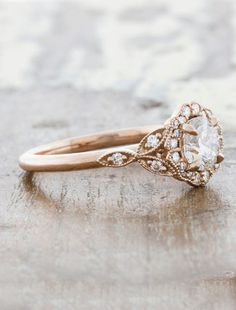 an antique style diamond ring on top of a wooden surface with the center stone surrounded by small diamonds