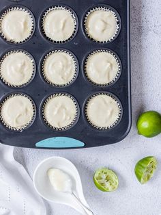 a muffin tin filled with cupcake batter next to limes