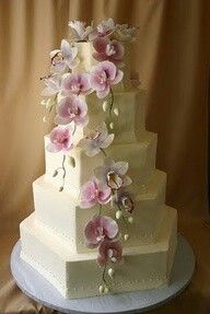 a three tiered white cake with pink flowers on top