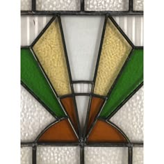 an old stained glass window with green, yellow and orange designs on the bottom half