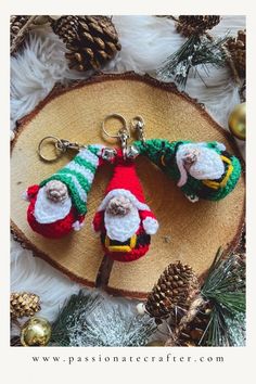 two knitted santa claus keychains sitting on top of a piece of wood