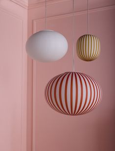 three striped lamps hanging from the ceiling in a room with pink walls and flooring