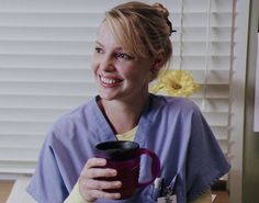 a woman in scrubs holding a coffee cup