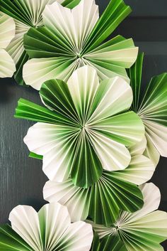 green and white paper flowers are hanging on the wall