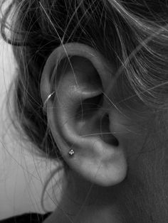 a woman's ear is shown with two piercings