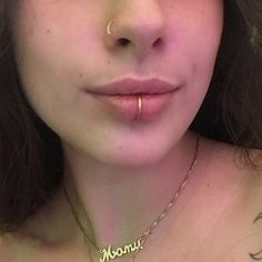 a woman with piercings on her nose is looking at the camera while wearing a necklace