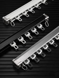 two black and white rails with clips attached to each other on a black surface,