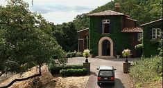 a car is parked in front of a house with ivy growing on it's walls