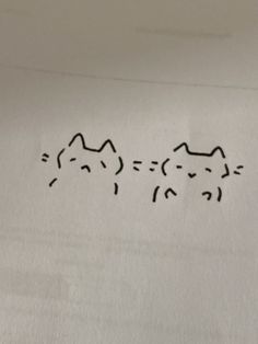 two cats are drawn on the side of a piece of white paper with black ink