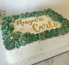 a white cake with green frosting and gold lettering