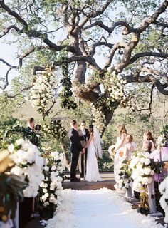 a bride and groom standing at the end of their wedding ceremony under an oak tree