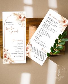 a wedding ceremony program with flowers and greenery on the front, in a wooden box