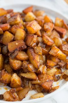 a white plate topped with cooked potatoes on top of a table