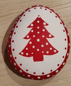 a red and white painted rock with a christmas tree on it