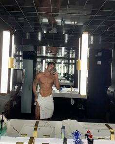 a shirtless man taking a selfie in front of a mirror