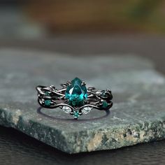 a close up of a ring on top of a piece of stone with green stones