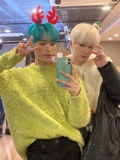 two young men standing next to each other in front of a mirror holding up their cell phones