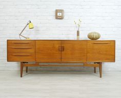 a sideboard with two lamps on it and a brick wall in the back ground