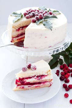 a cake with white frosting and cranberry filling on a plate next to berries