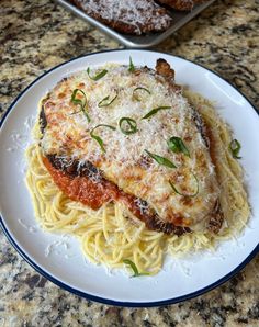 a white plate topped with pasta and meat covered in sauce on top of a counter