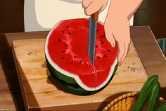 a person cutting up a piece of watermelon with a knife