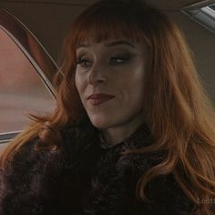 a woman with red hair sitting in a car