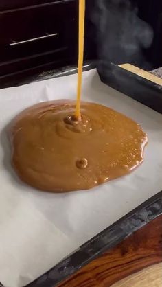 a person pouring liquid into a pan with food in it on top of wax paper