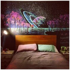 a bed sitting under a painting next to a night sky filled with stars and planets