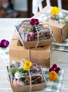 three boxes filled with food sitting on top of a table covered in paper and twine