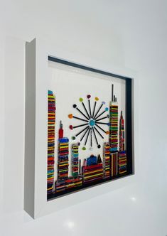 a clock made out of crayons and pencils on a white wall with a cityscape in the background