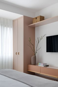 there is a television on the wall in this bedroom with pink walls and white curtains