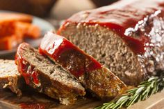 sliced meatloaf with ketchup and rosemary on cutting board