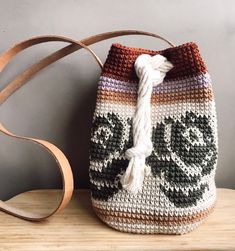 a crocheted bag sitting on top of a wooden table next to a purse