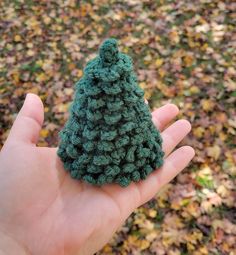 a small crocheted christmas tree sitting in someone's hand on the ground