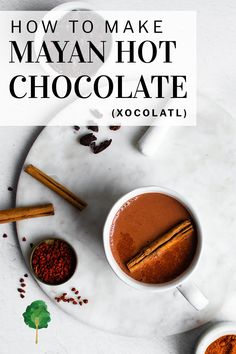 two cups of hot chocolate on a plate with cinnamons and spices next to it