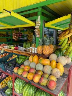 there are many different fruits on display at the market stall, including bananas, pineapples, watermelon, and melons